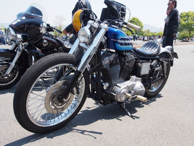 two motorcycles parked next to each other in a parking lot with people looking at them