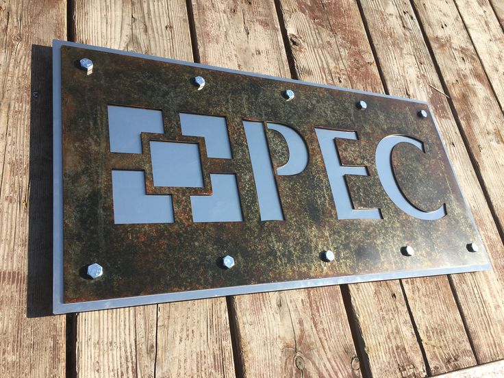 a metal sign that reads epec on the side of a wooden wall with rivets