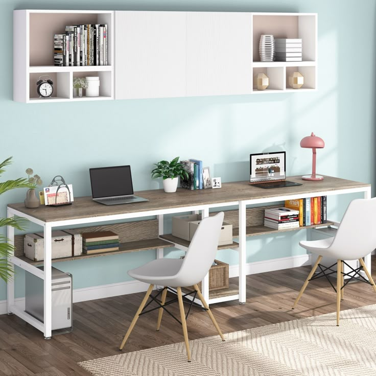 a computer desk with two chairs and a laptop on it in front of a blue wall