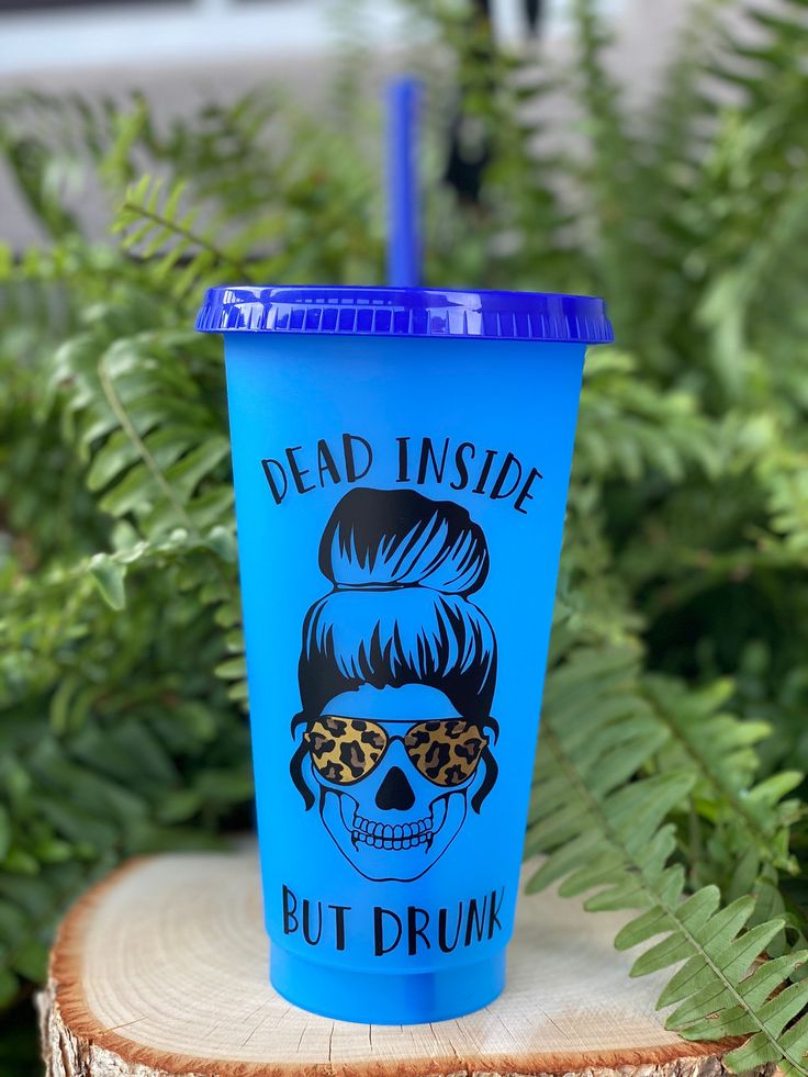 a blue cup sitting on top of a tree stump in front of some green plants