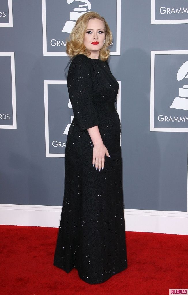 a woman in a black dress on the red carpet at an awards event with her hand on her hip