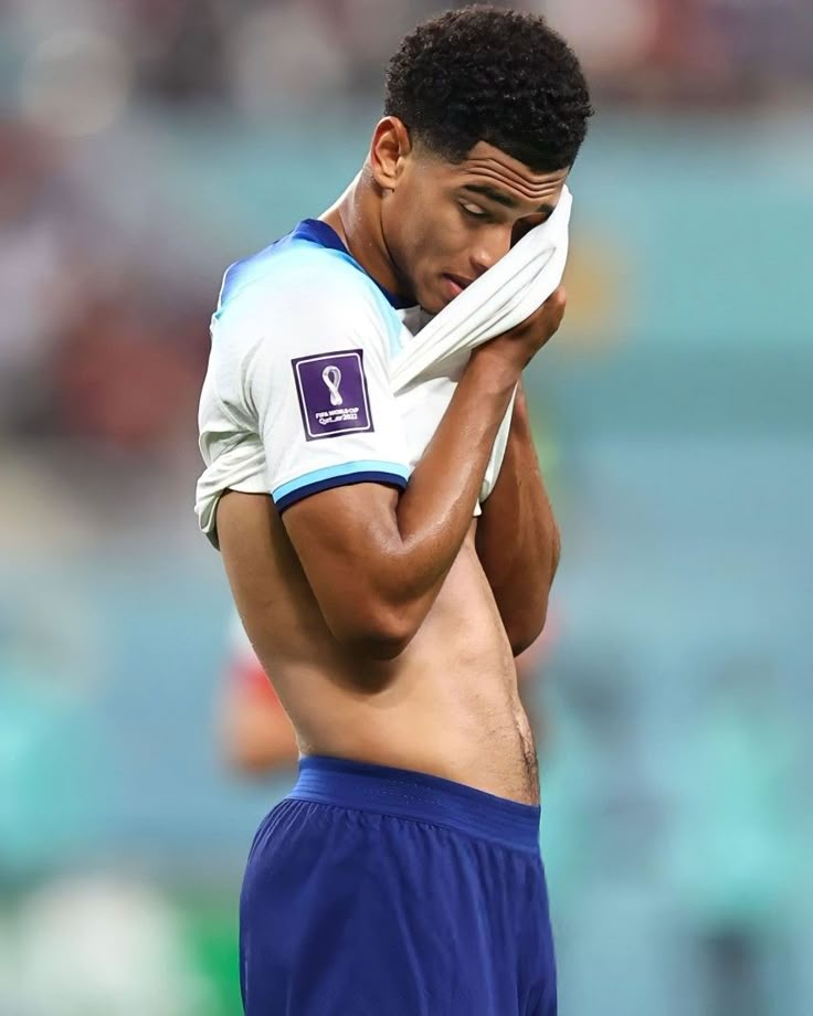 a shirtless soccer player wiping his face