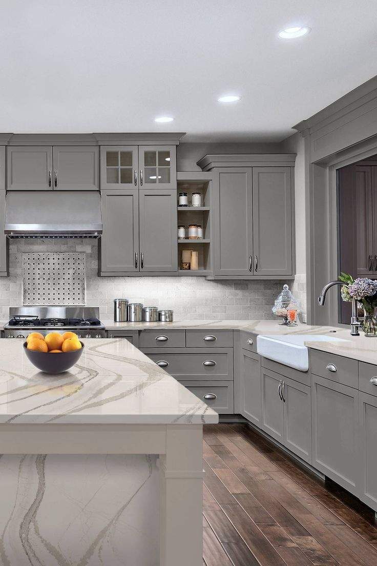 a kitchen with gray cabinets and marble counter tops