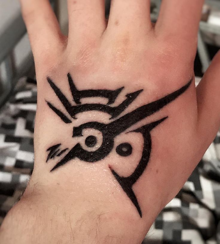 a person's hand with a black ink tattoo design on the middle of it