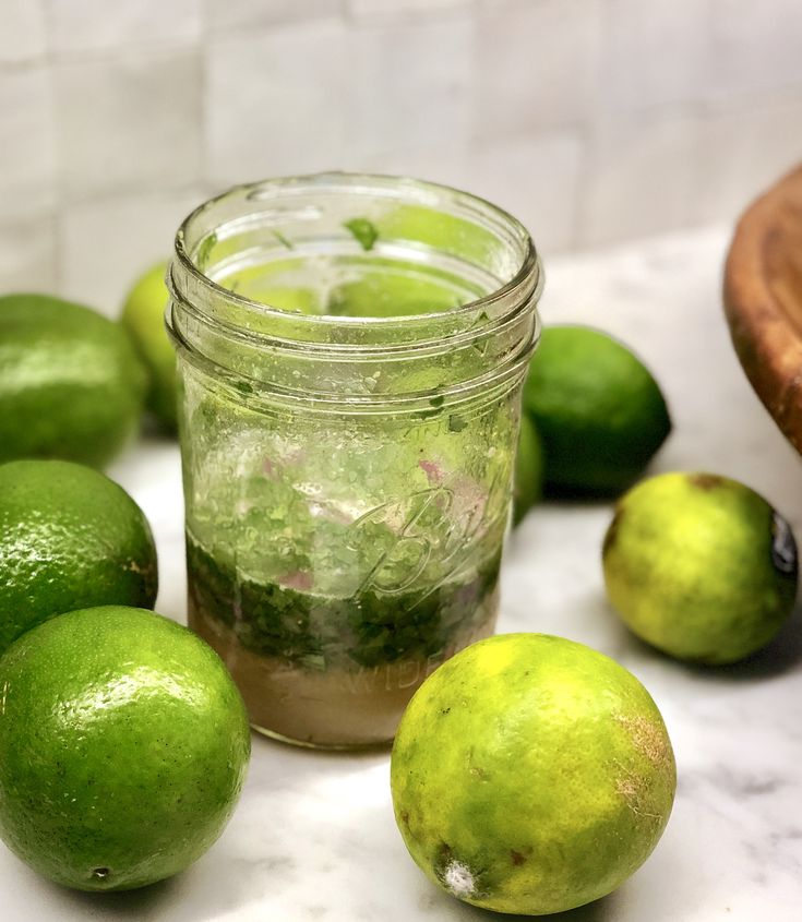 limes are sitting on the counter next to a mason jar