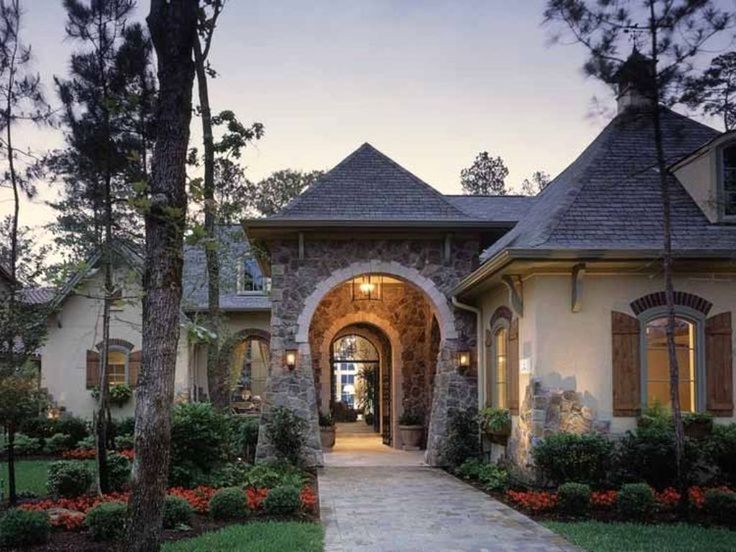 the entrance to a large home surrounded by trees