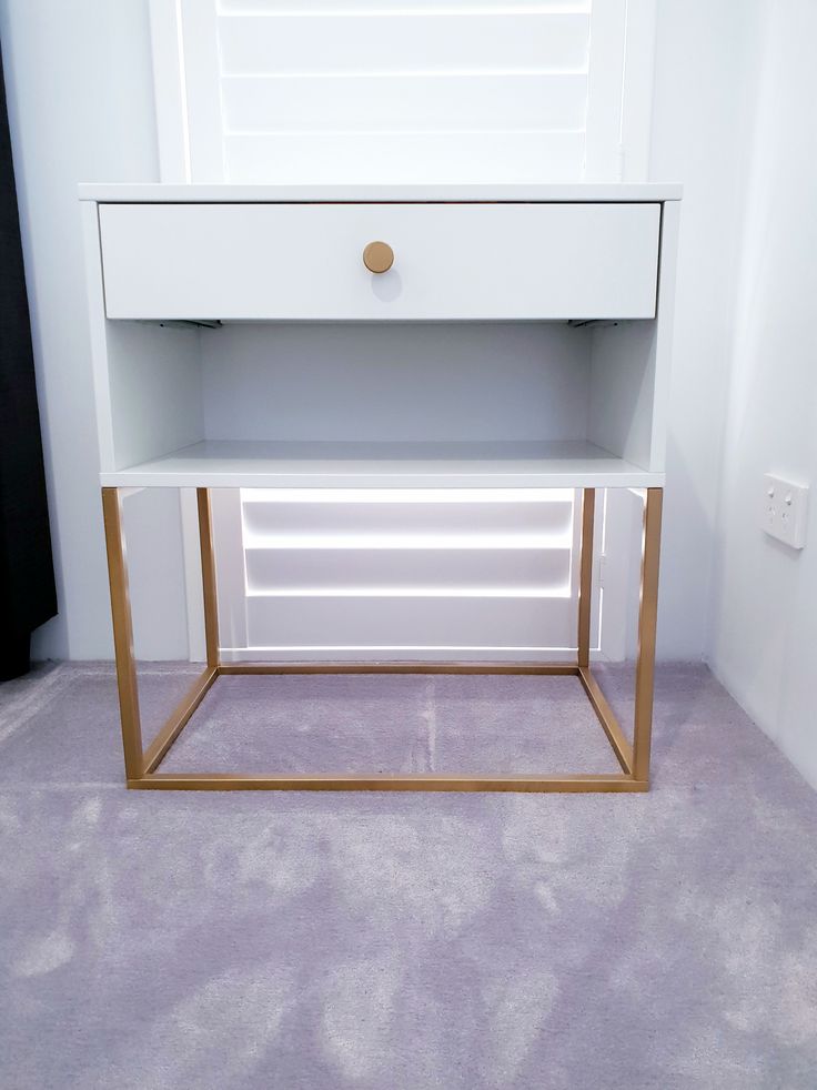 a white and gold nightstand in a small room with purple carpeting on the floor