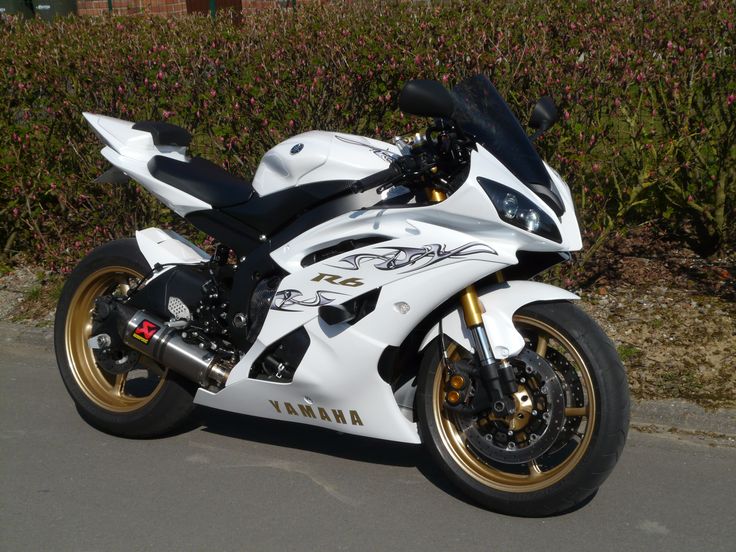 a white and black motorcycle parked on the side of a road next to some bushes