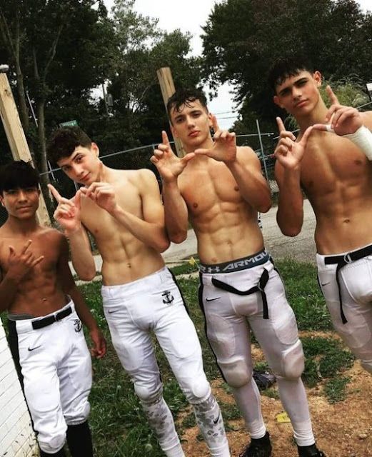 four young men in white pants posing for the camera with one pointing to his left