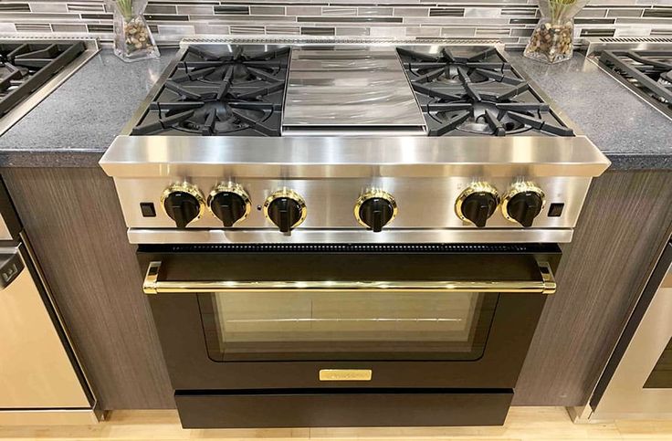 a stainless steel stove with four burners and two oven doors, in a kitchen