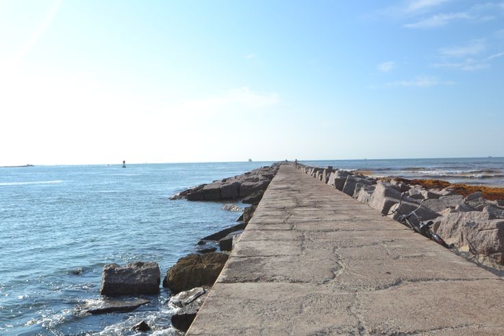 there is a long concrete pier that extends into the water and stretches out to sea