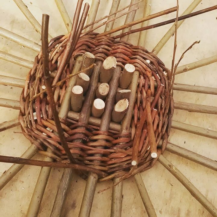 a wicker basket filled with lots of wooden sticks and wood dows sitting on top of a floor