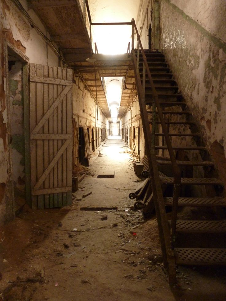 an alley way with stairs leading up to two sets of wooden doors and railings