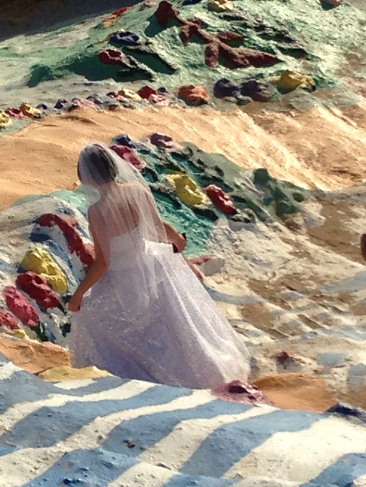 a woman in a wedding dress walking on the beach