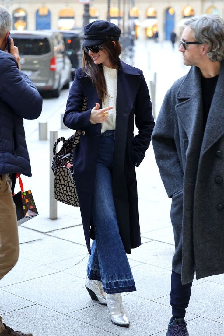 the woman is walking down the street talking on her cell phone while wearing jeans and a coat