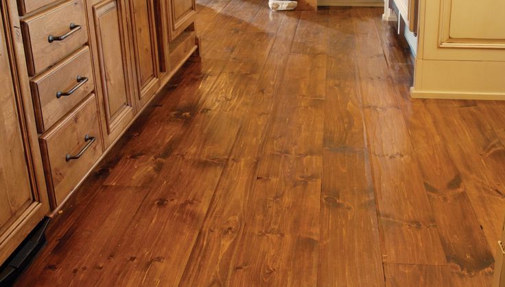 a wooden floor in a kitchen with cabinets and counter tops on either side of the room