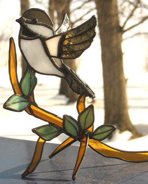 a stained glass bird sitting on top of a branch