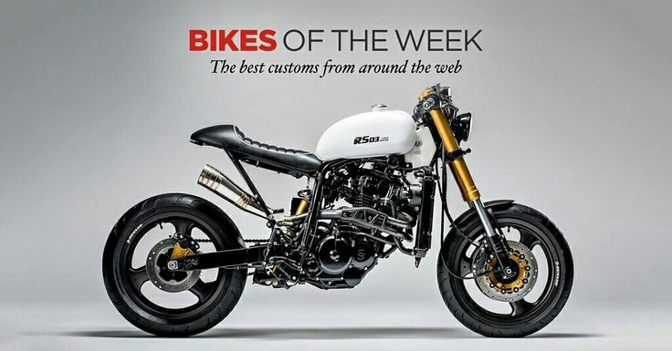 a white and black motorcycle parked on top of a gray floor next to a wall