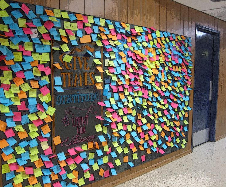 a bulletin board with post it notes attached to the wall and writing on the back