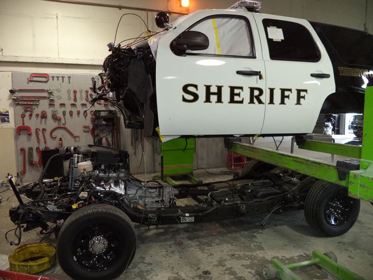 there is a white truck with the word sheriff written on it's side in a garage