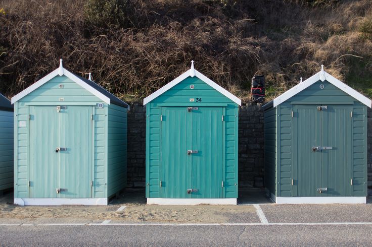 three rows of beach huts sitting next to each other on the side of a road