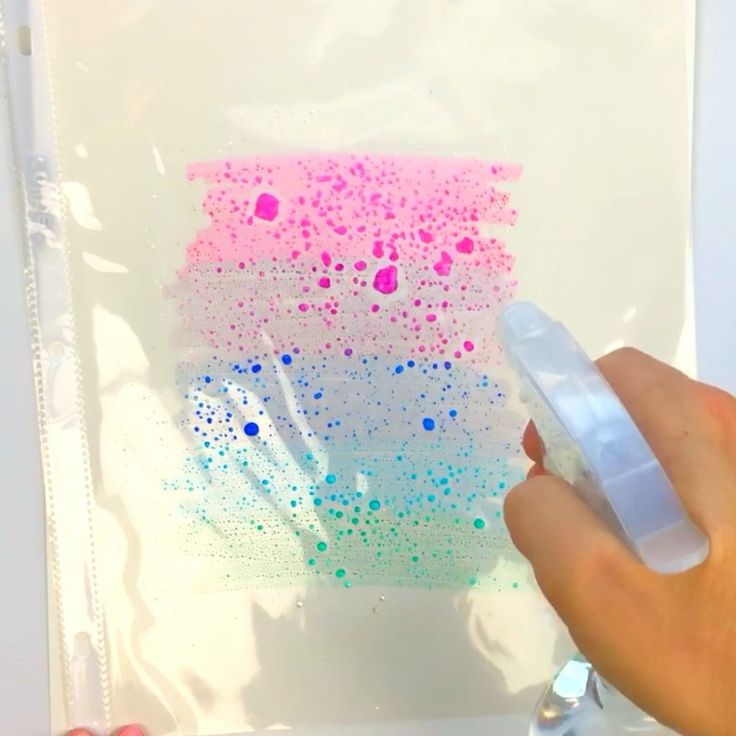 a person is holding a marker in front of a piece of paper that has sprinkles on it