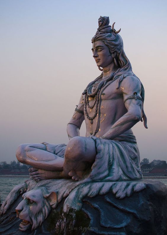 a statue of a man sitting on top of a lion next to a body of water