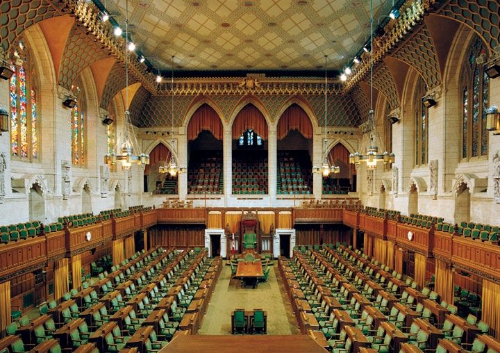 the interior of a large building with rows of green chairs and wooden paneling on the walls