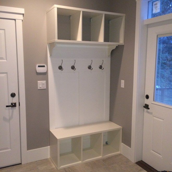 a white coat rack with three coats on it and two doors open to the other side