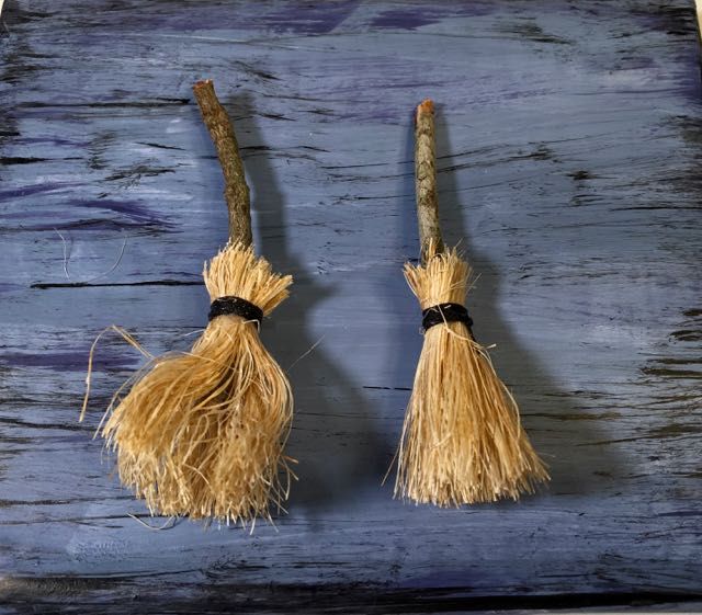 two tasseled brooms sitting on top of a wooden table