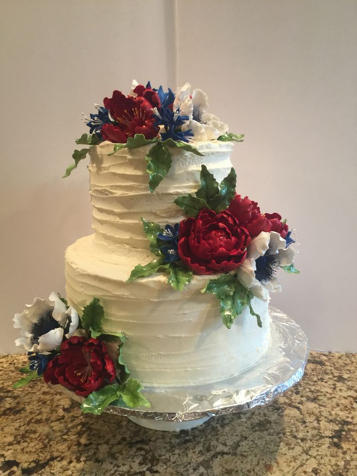 a three tiered cake with red, white and blue flowers on the top layer