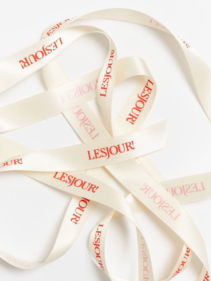 white ribbon with red words on it laying on top of each other in the shape of a heart