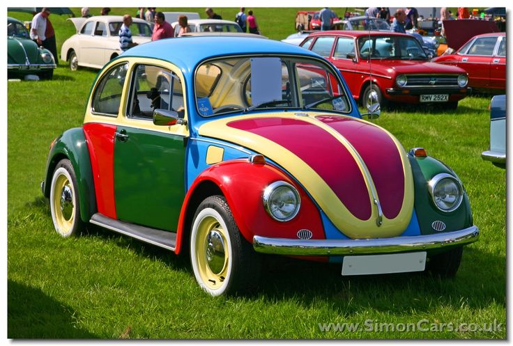 a colorful beetle parked in the grass at a car show