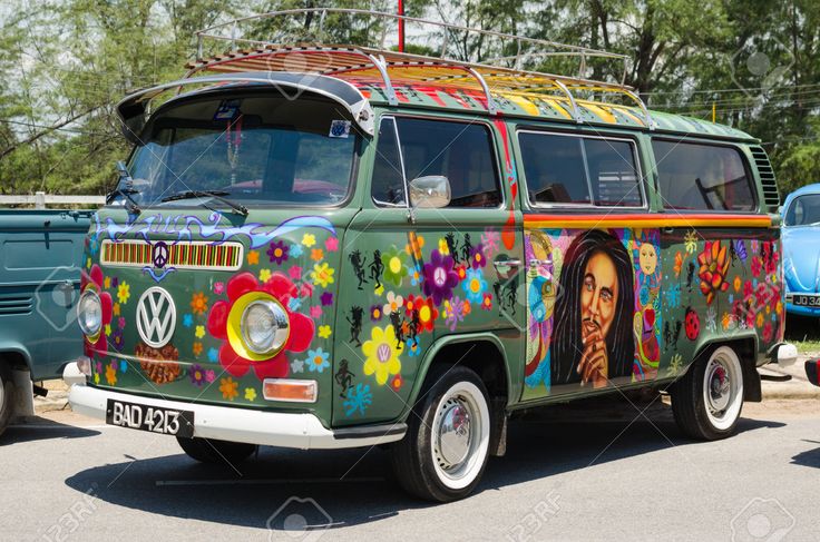 an old vw bus painted with colorful flowers and people's faces is parked in a parking lot