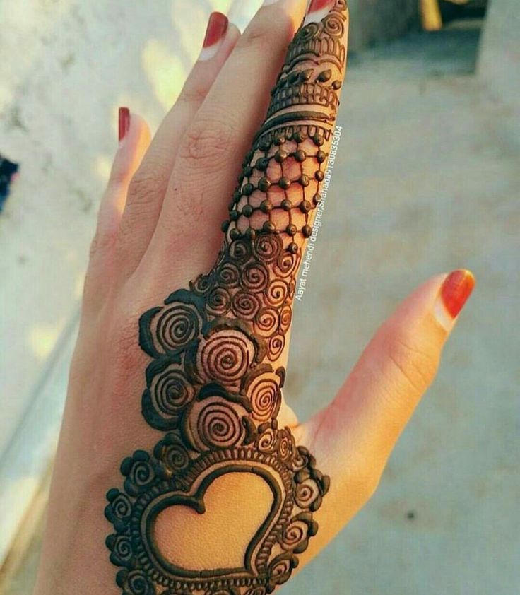 a woman's hand with a henna on it and a heart drawn in the middle