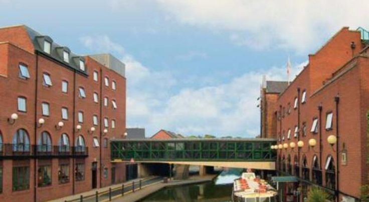 a boat traveling down a river next to tall brick buildings with windows on each side