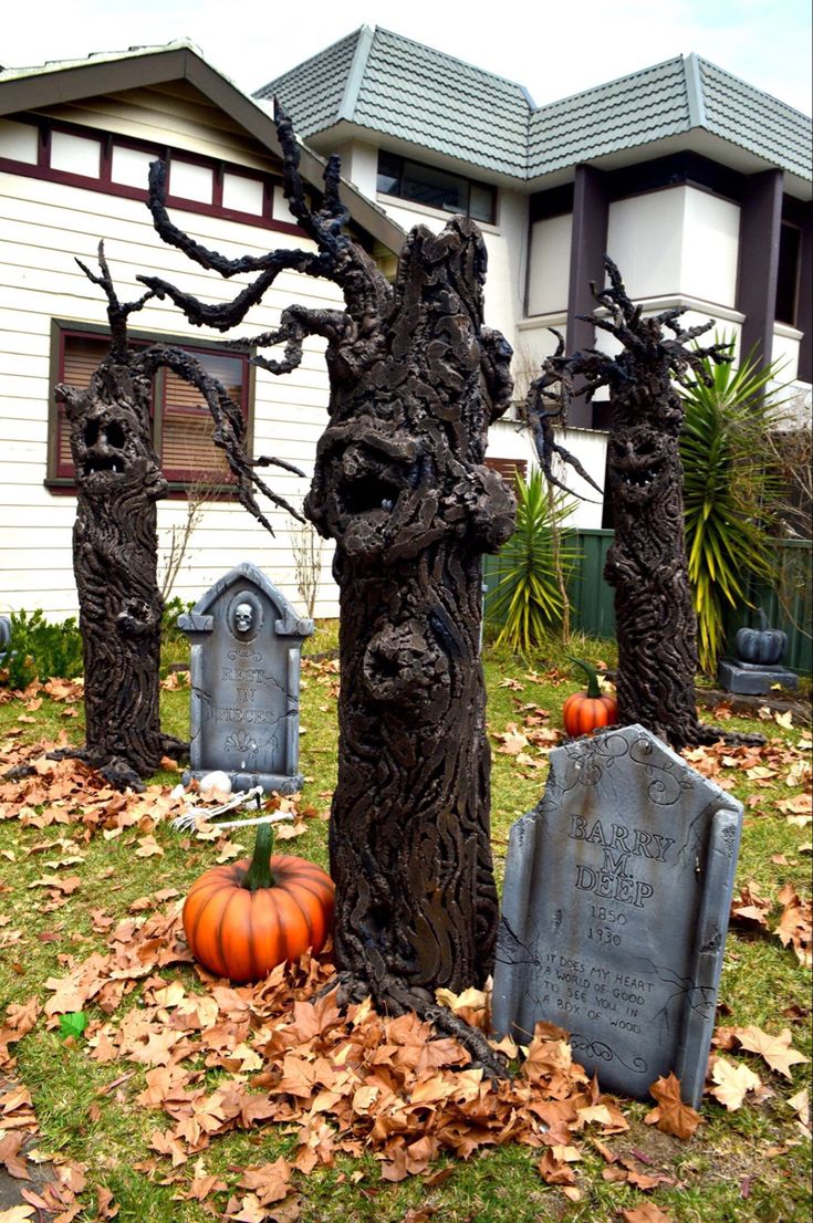 a cemetery with tombstones and pumpkins on the ground in front of a house