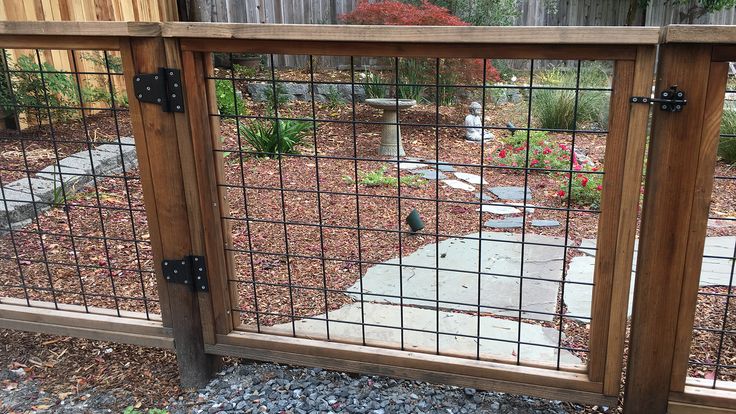 the gate is made out of wood and has metal bars on it, along with gravel