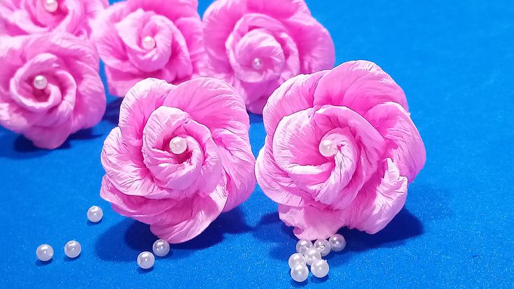 some pink flowers and pearls on a blue surface