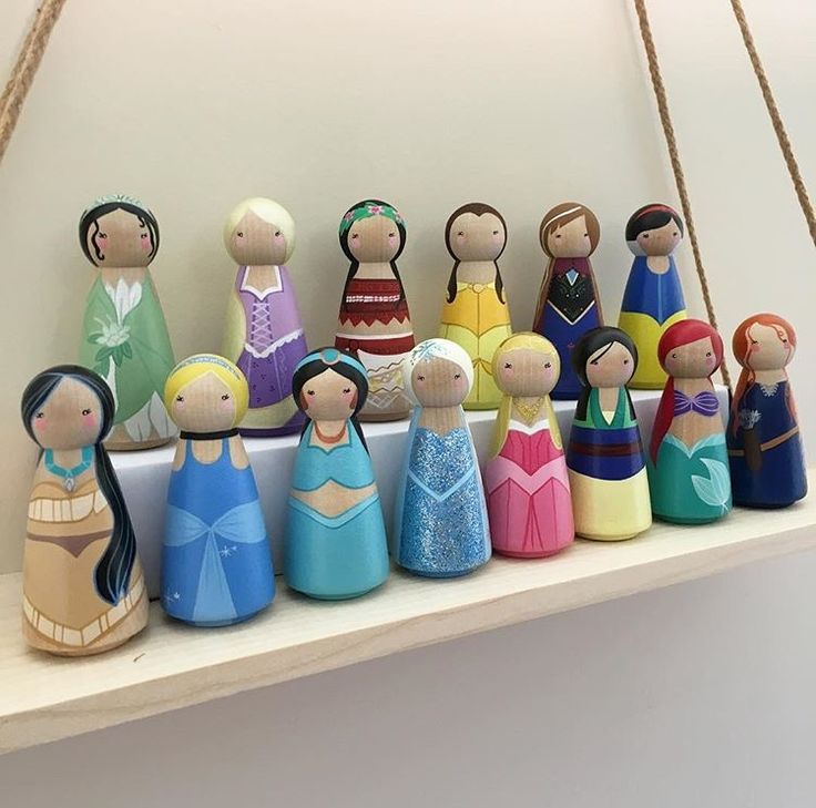 a group of wooden dolls sitting on top of a white shelf next to each other