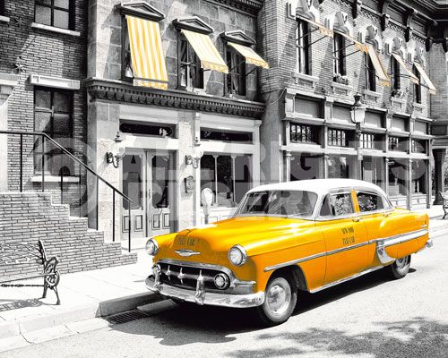 an old yellow car parked in front of a tall building on the side of the road