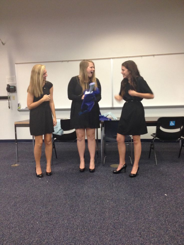 three young women standing in front of a whiteboard talking to each other and laughing