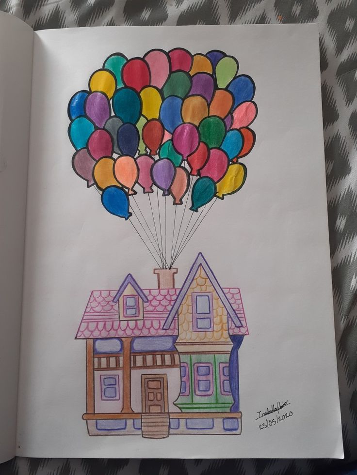 an open book with a drawing of a house and balloons