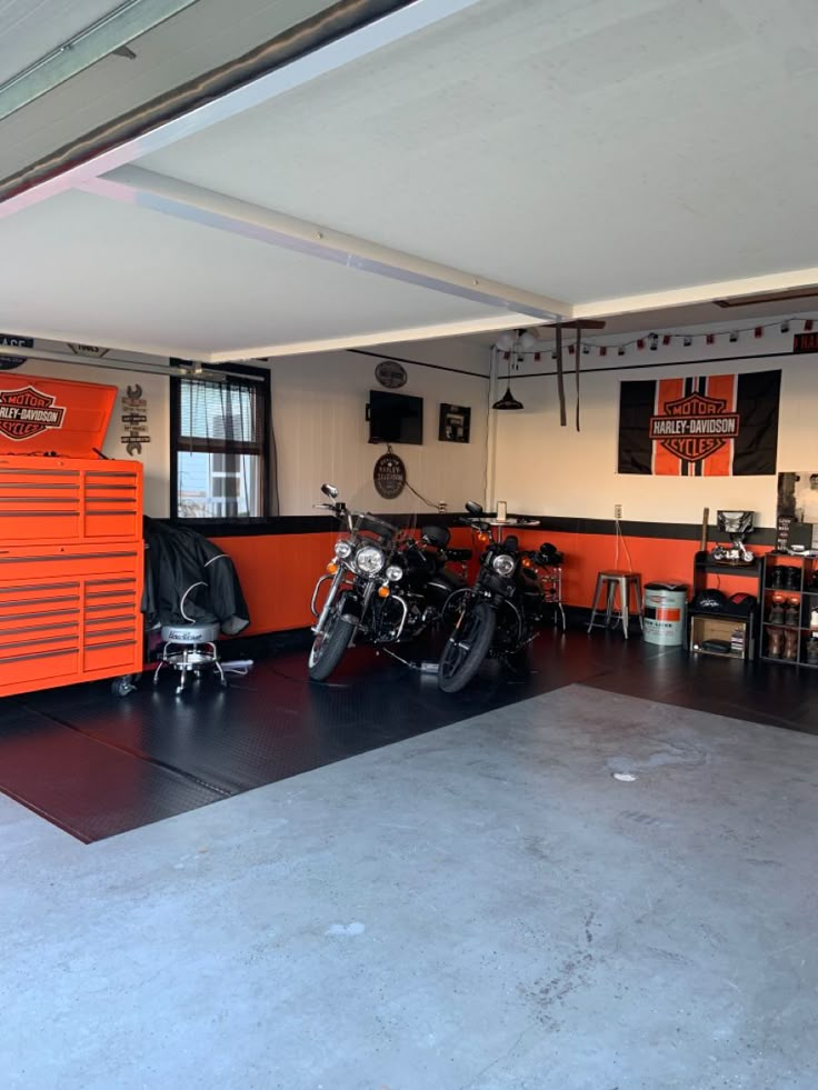 an orange motorcycle is parked in a garage with other motorcycles and tables on the floor