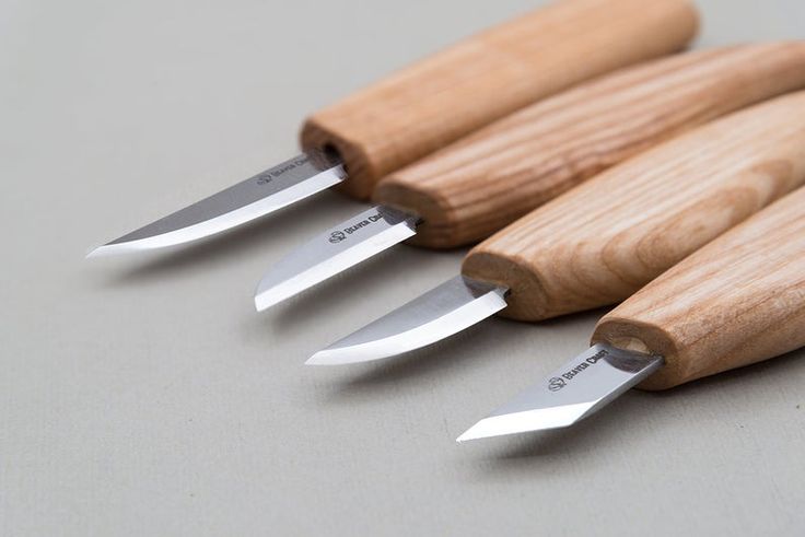 four knives are lined up next to each other on a gray surface with wood handles