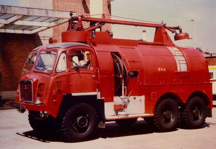 an old red fire truck parked in front of a building