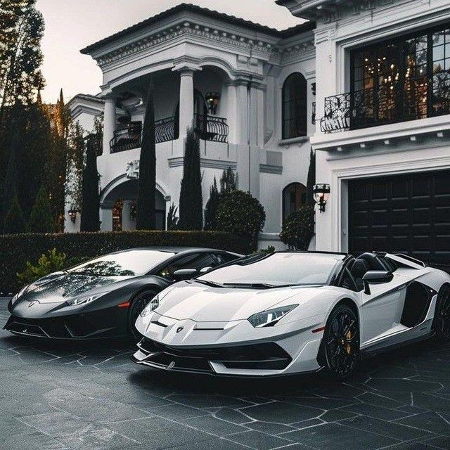 two white and black sports cars parked in front of a house