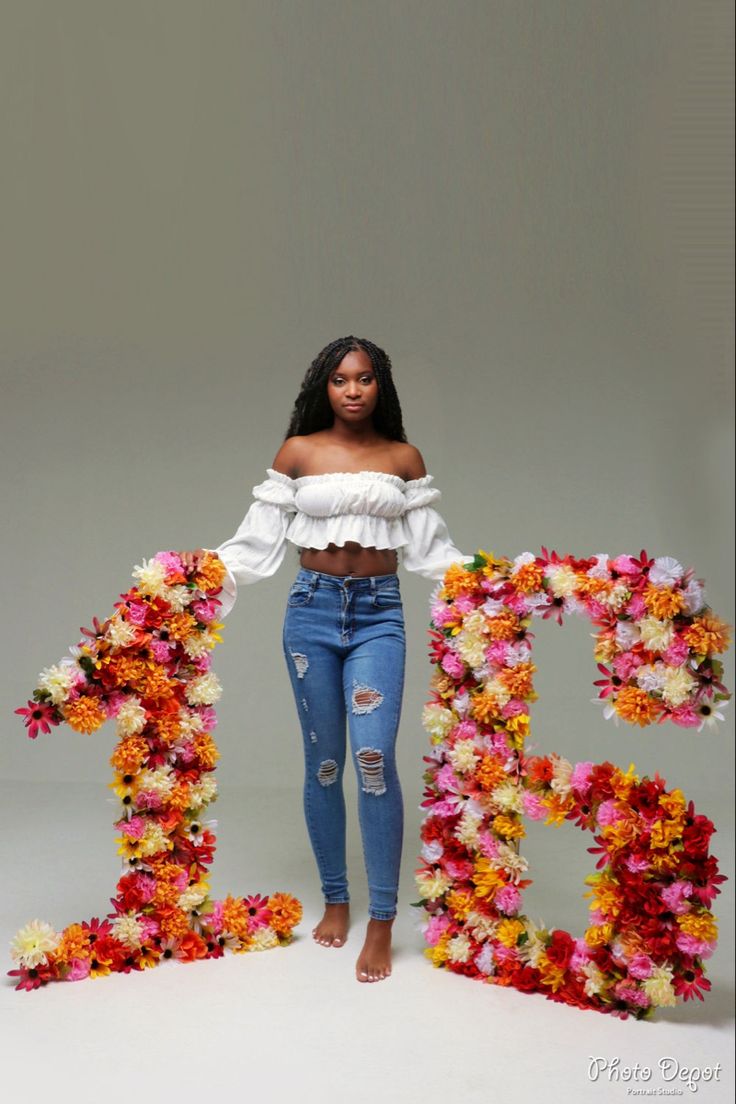 a woman standing in front of the word b is made out of flowers