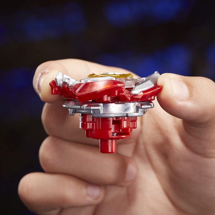 a hand holding a red toy car in it's right hand and the top part of its engine visible