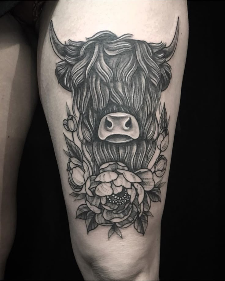 a black and white photo of a bull with flowers on it's leg,